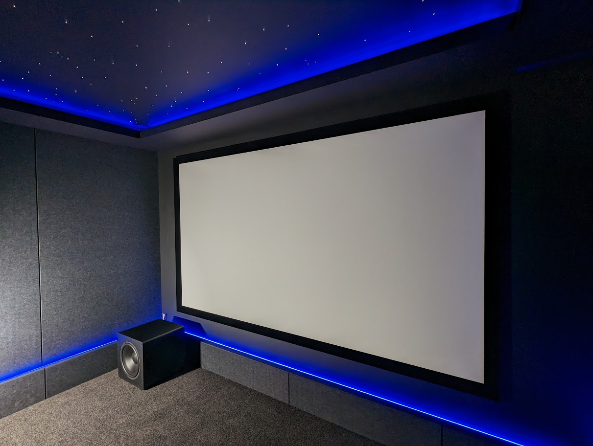 Dedicated home cinema with large projection screen and blue architectural lighting